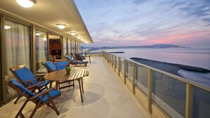 A balcony with blue chairs and a wooden table, overlooking a beach at sunset. - Mövenpick Hotel & Casino Malabata Tanger (Tangier)