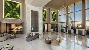 A spacious lobby with a reception desk, seating areas, and large windows offering views of greenery. - Mövenpick Hotel & Casino Malabata Tanger (Tangier)