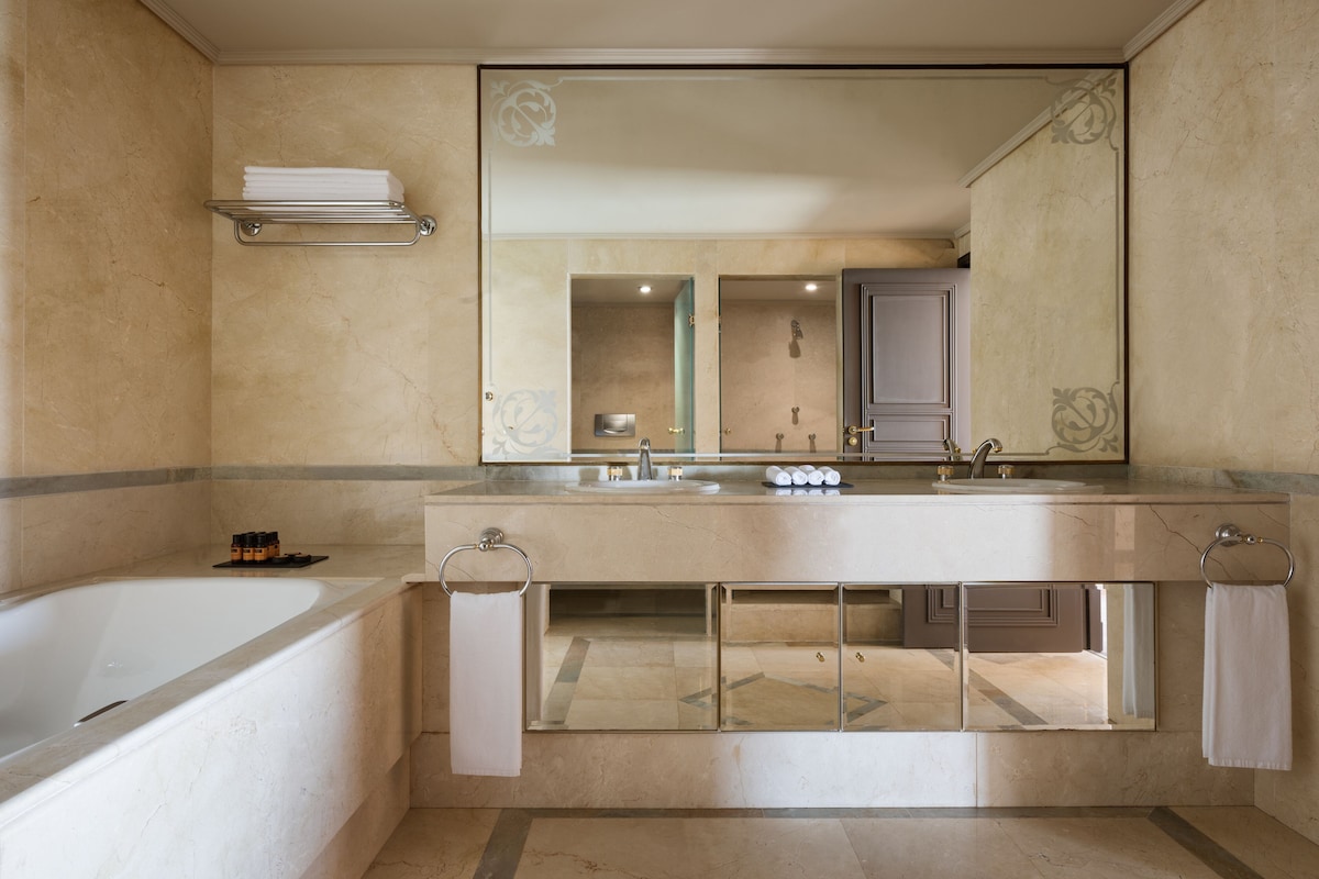 A modern bathroom with a bathtub, a large mirror, and a vanity with a sink.