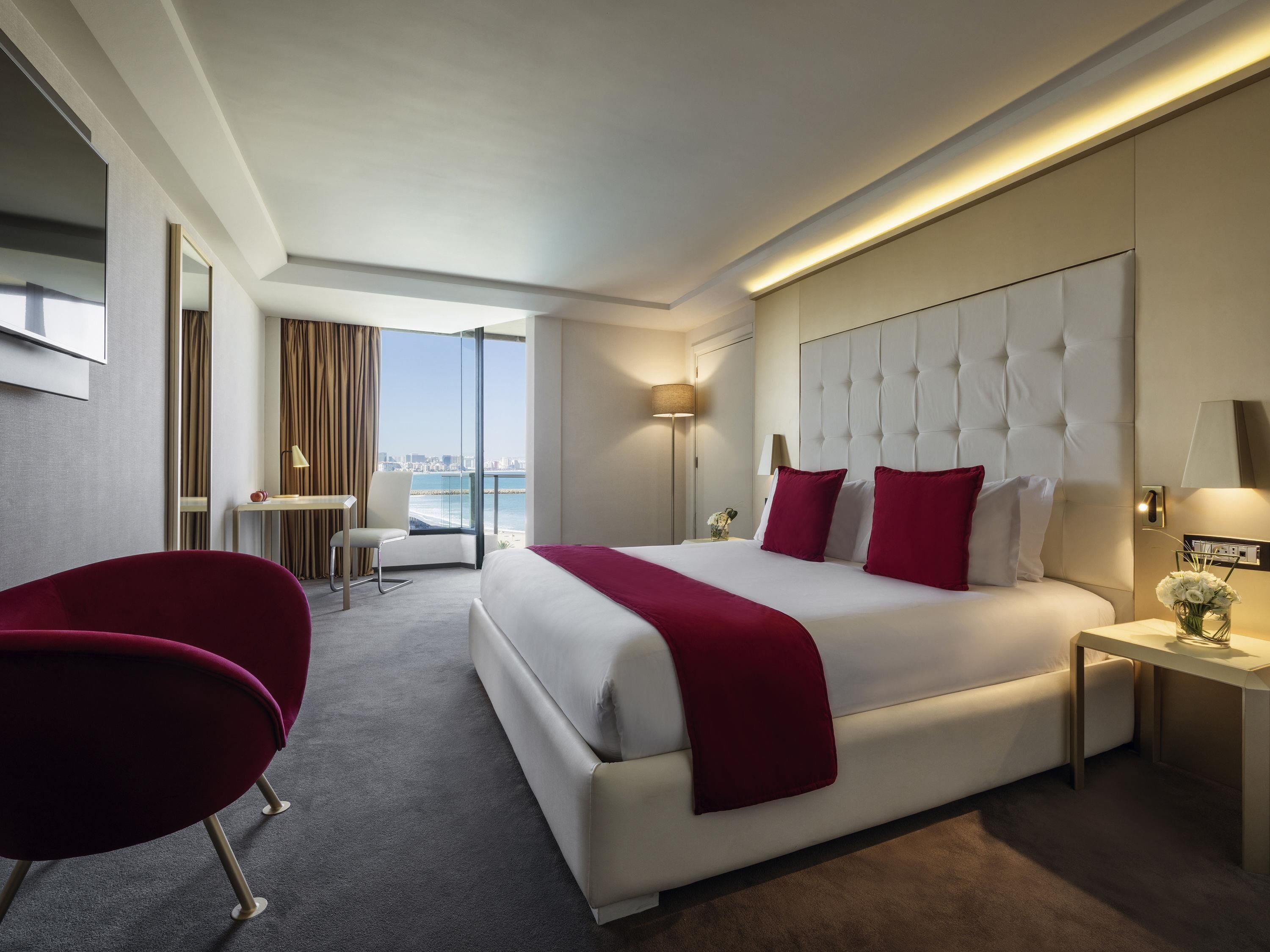Une chambre d’hôtel avec un grand lit, un bureau, une chaise et une vue sur la ville.