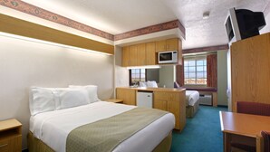 Une chambre d’hôtel équipée d’un lit, d’un bureau, d’un four à micro-ondes, d’un petit réfrigérateur et d’une fenêtre donnant sur un paysage agréable.