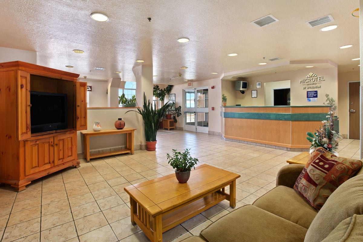 A hotel lobby with a reception desk, a television, a coffee table, and a sofa.