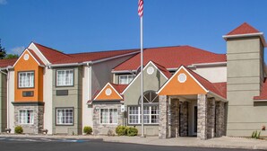 A row of modern multi-story buildings with a uniform architectural style, featuring a mix of stone and stucco exteriors, red roofs, and a central flagpole with an American flag.