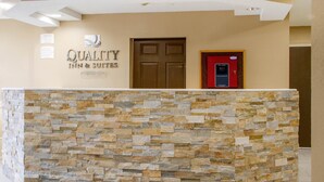 A reception area with a stone wall, a door, and a sign for Quality Inn & Suites.
