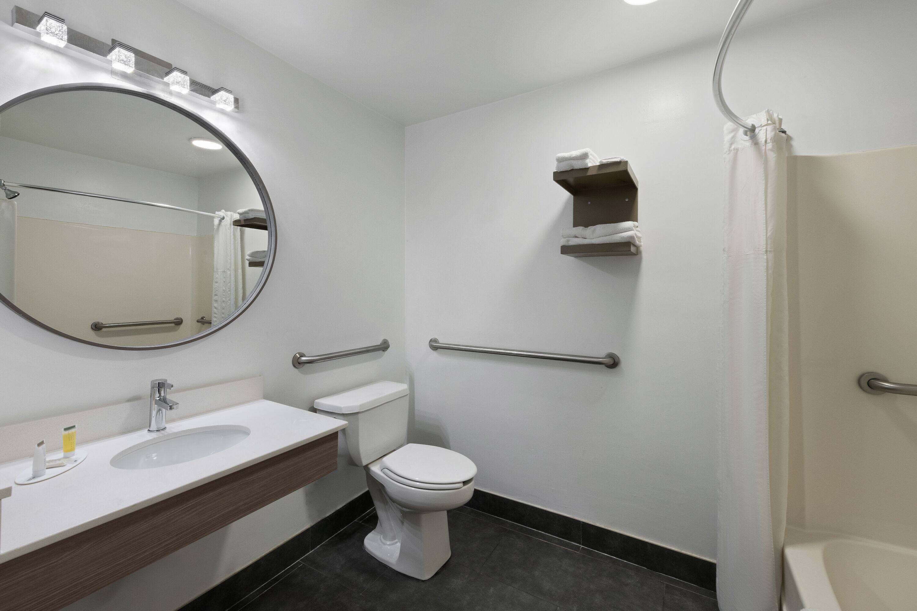 Une salle de bain avec un lavabo blanc, des toilettes, un miroir et une douche.