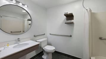 Une salle de bain avec un lavabo blanc, des toilettes, un miroir et une douche.