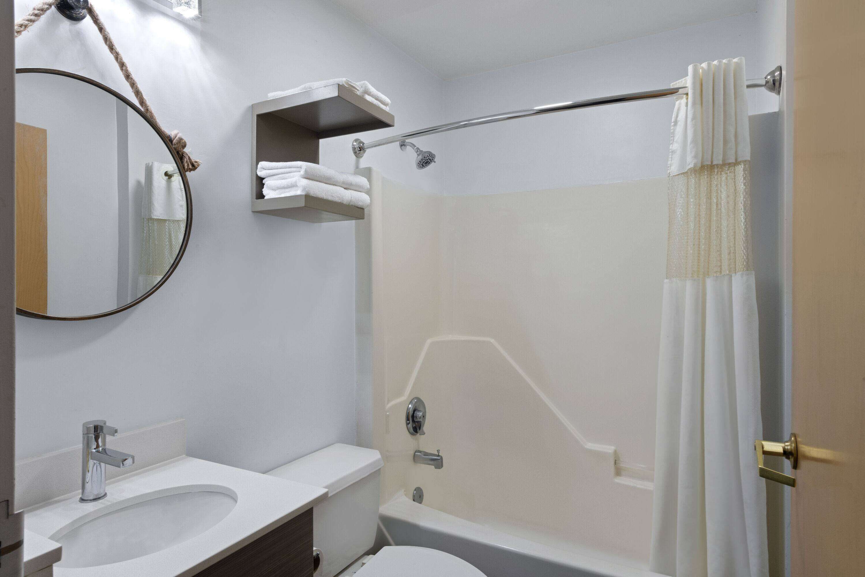 Un baño moderno con una bañera, un inodoro, un lavabo, un espejo y un perchero para toallas.