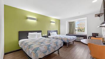Habitación de hotel con dos camas, una mesa de comedor y un televisor.