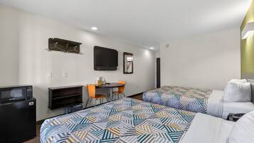 A hotel room with two beds, a desk, a chair, a TV, and a microwave.