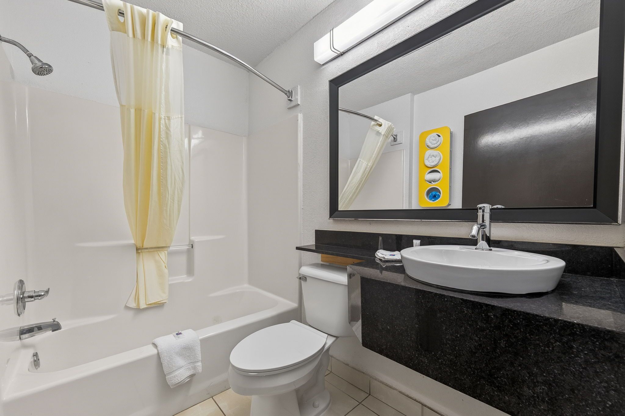 A bathroom with a bathtub, toilet, sink, and a mirror with a towel rack.