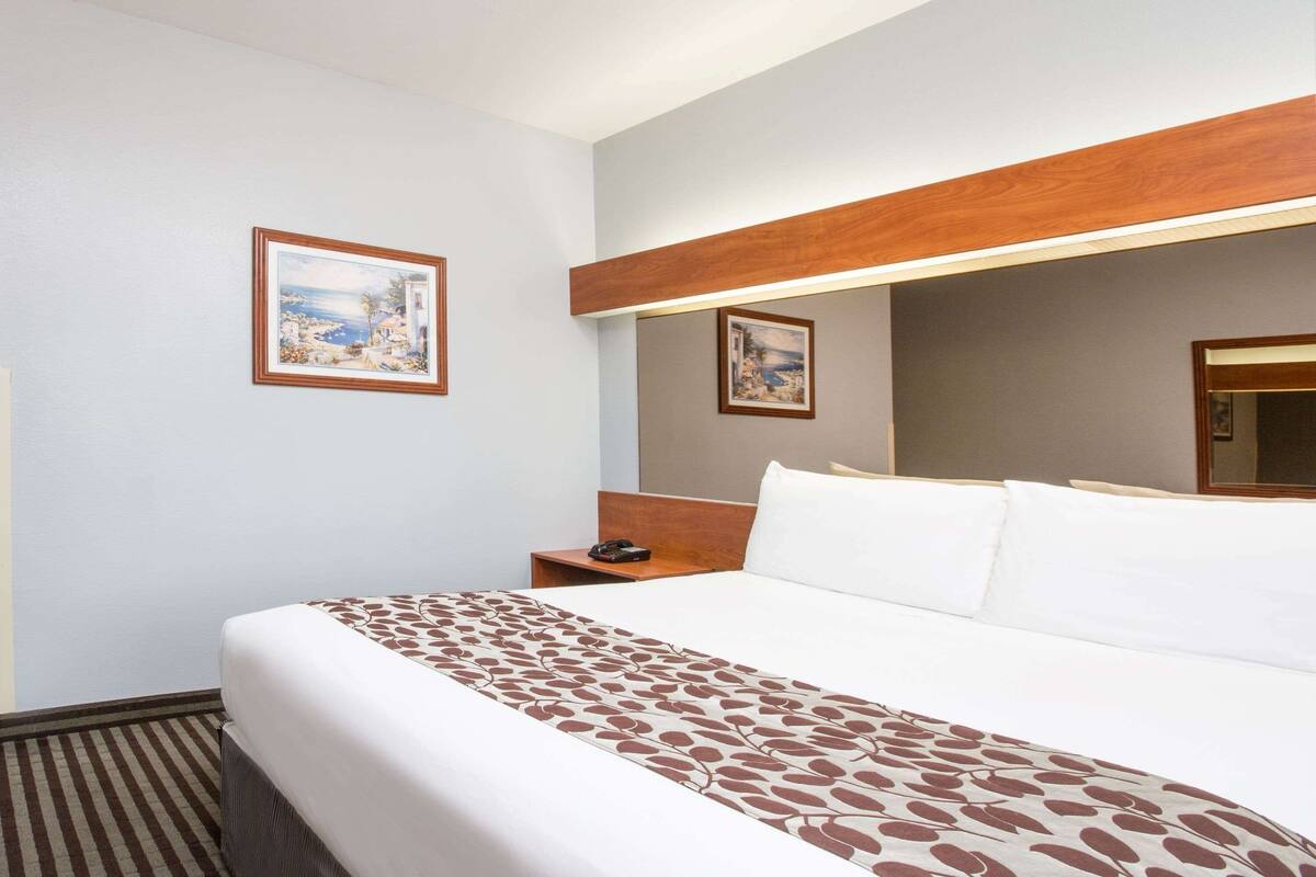 Ein Hotelzimmer mit einem großen Bett, einem Holz-Kopfteil, zwei Nachttischen und zwei gerahmten Bildern an den Wänden.