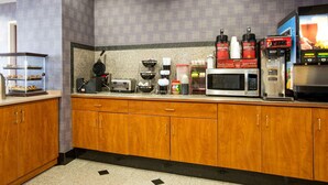 Una cocina con armarios de madera, una cafetera, un microondas y un tostador.