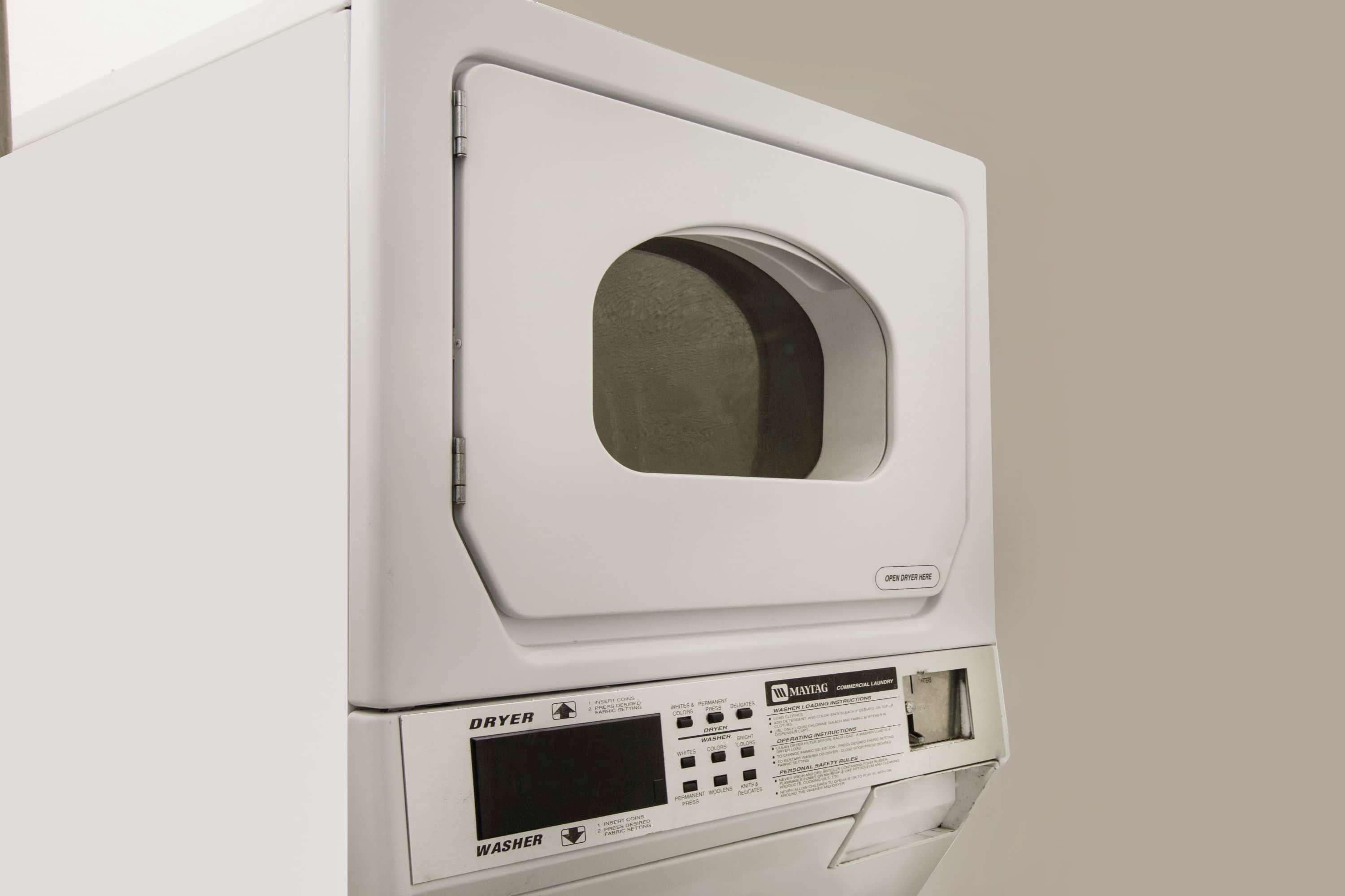 A white commercial laundry machine with a control panel and a door.