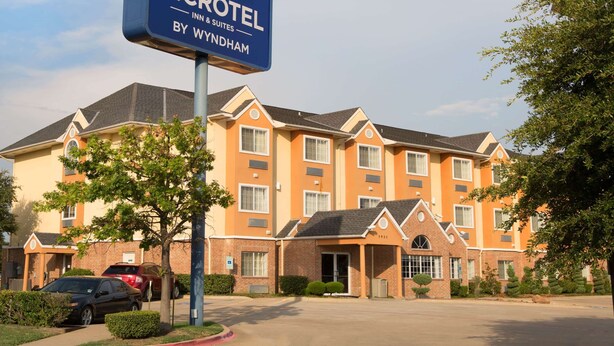 Edificio de Microtel Inn & Suites con fachada de ladrillo, múltiples ventanas y un estacionamiento con automóviles.