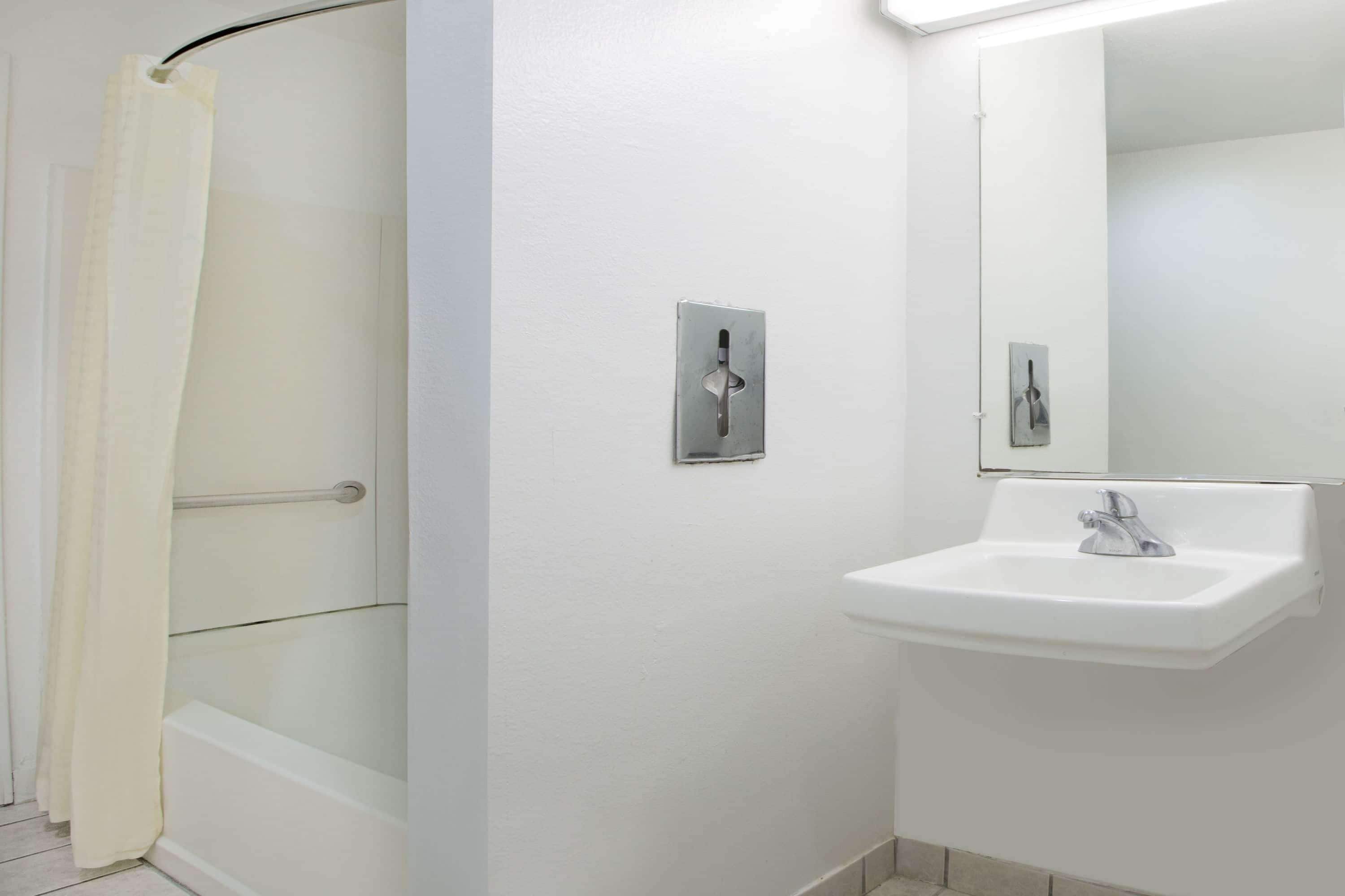 Baño con ducha, lavamanos y espejo.
