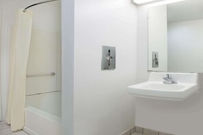 A bathroom with a shower, a sink, and a mirror.