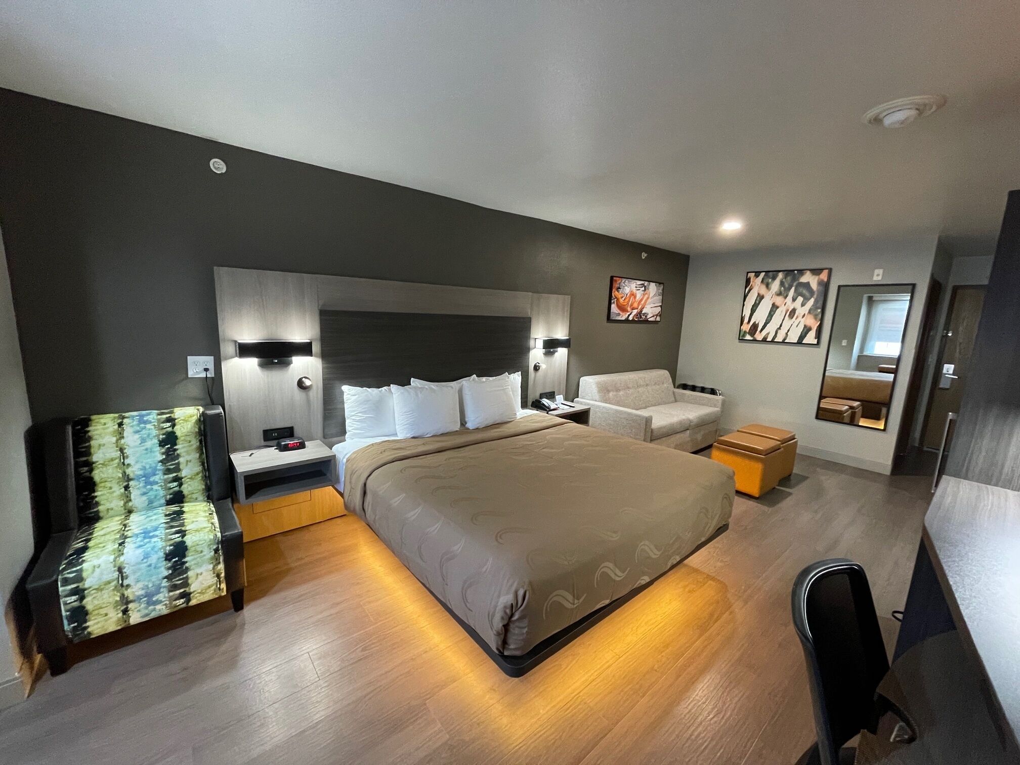 Une chambre d’hôtel moderne avec un grand lit, des tables de chevet, un canapé et une petite table.