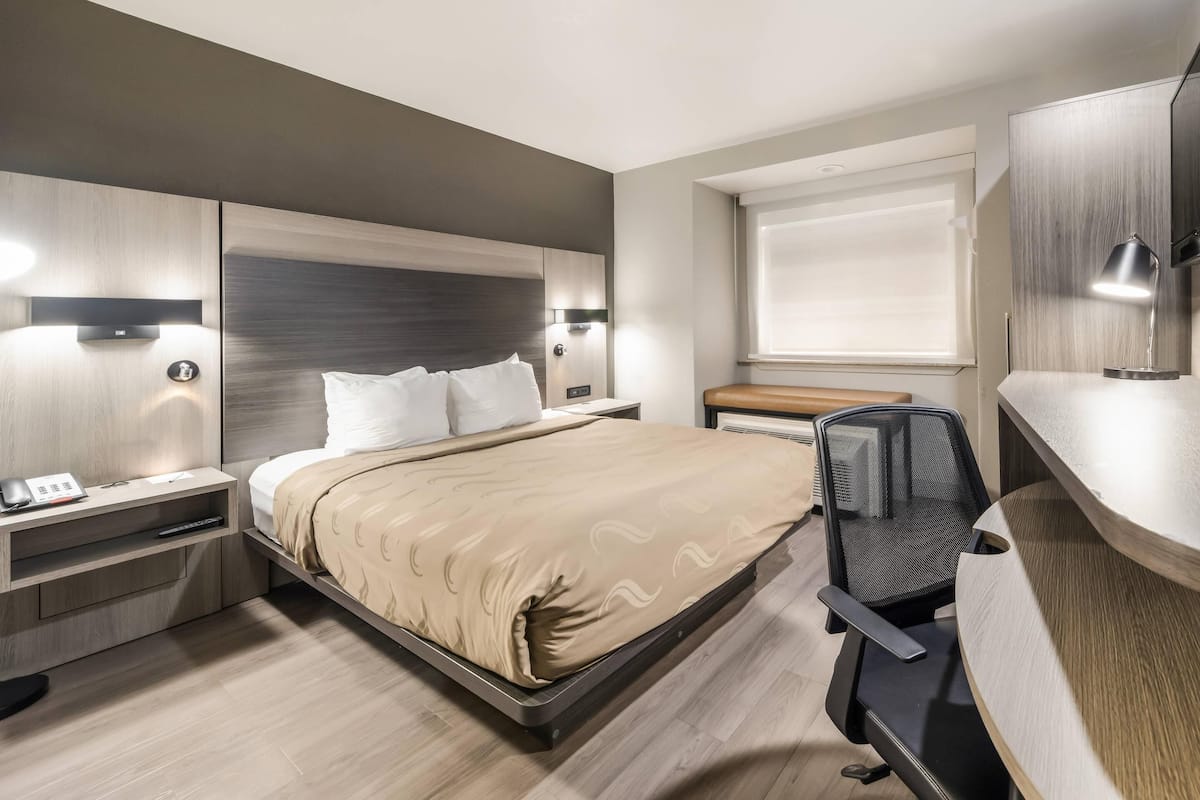 Une chambre d’hôtel moderne équipée d’un lit, de tables de chevet, d’un bureau et d’une chaise.