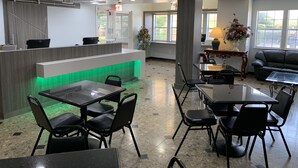 A modern reception area with a desk, chairs, and a green-lit counter. - Quality Inn & Suites North Mesquite I-30 (Mesquite)