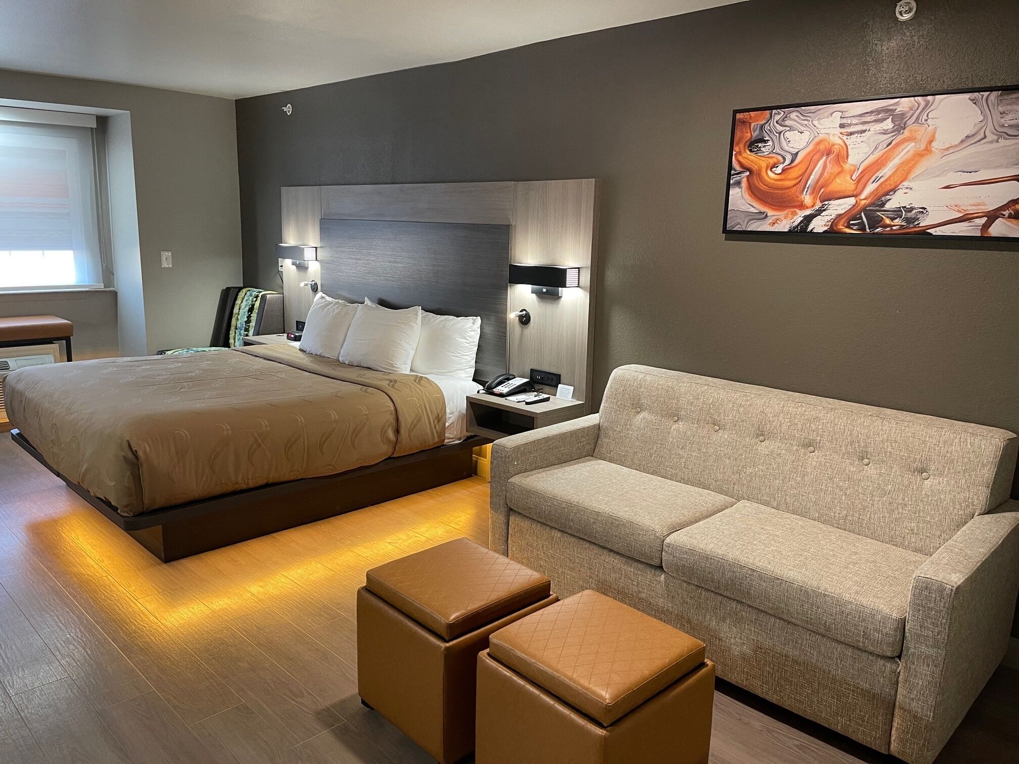 Una habitación de hotel con una cama grande, un sofá y dos otomanas.