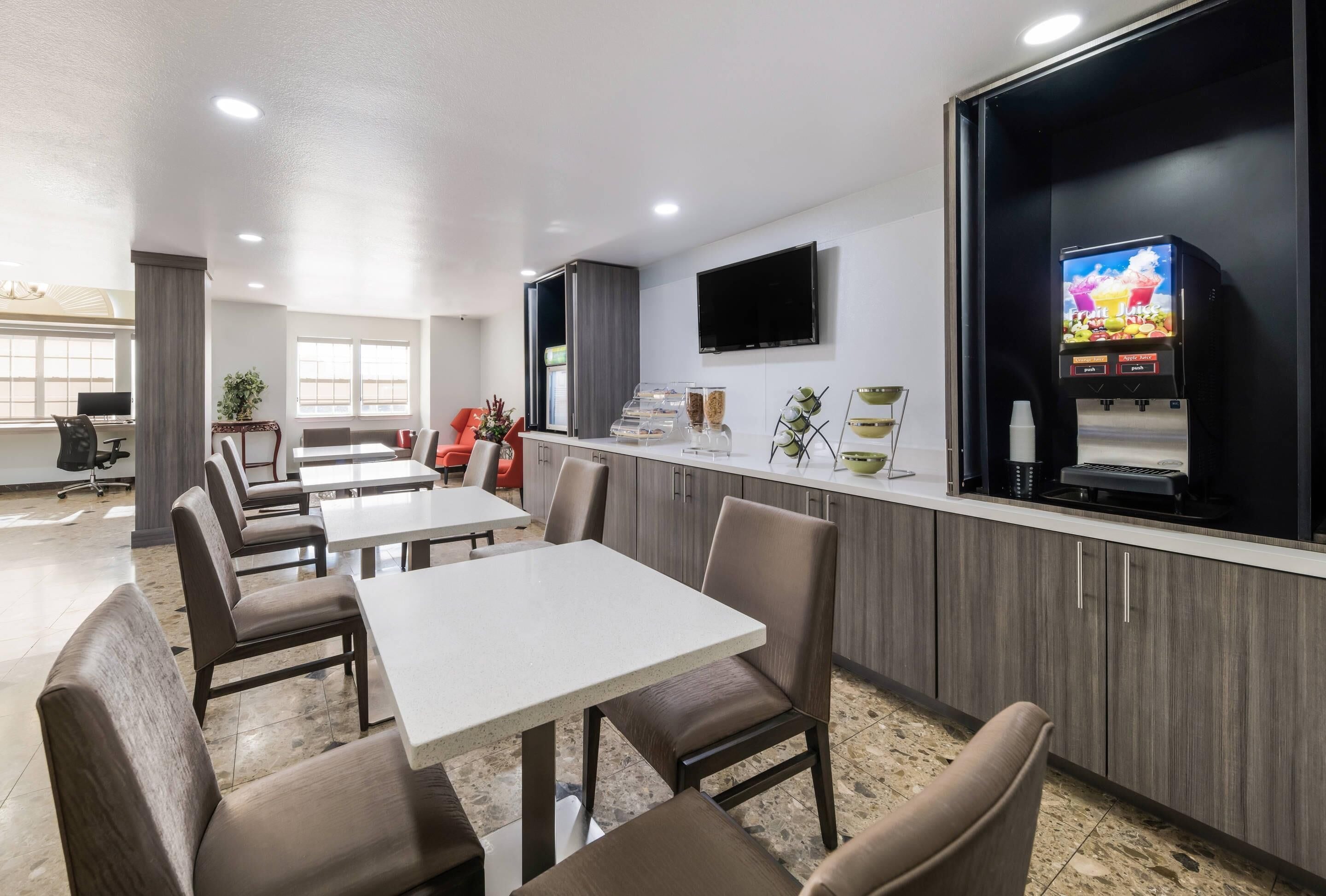 A modern restaurant with a counter, seating area, and a television screen.