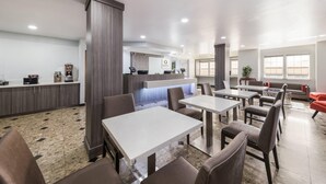 A modern dining area with tables and chairs, a kitchen area with a counter, and a seating area with a sofa. - Quality Inn & Suites North Mesquite I-30 (Mesquite)