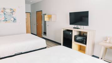 Habitación de hotel con dos camas, televisión, microondas y una mesita.