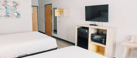 A hotel room with two beds, a television, a microwave, and a small table.