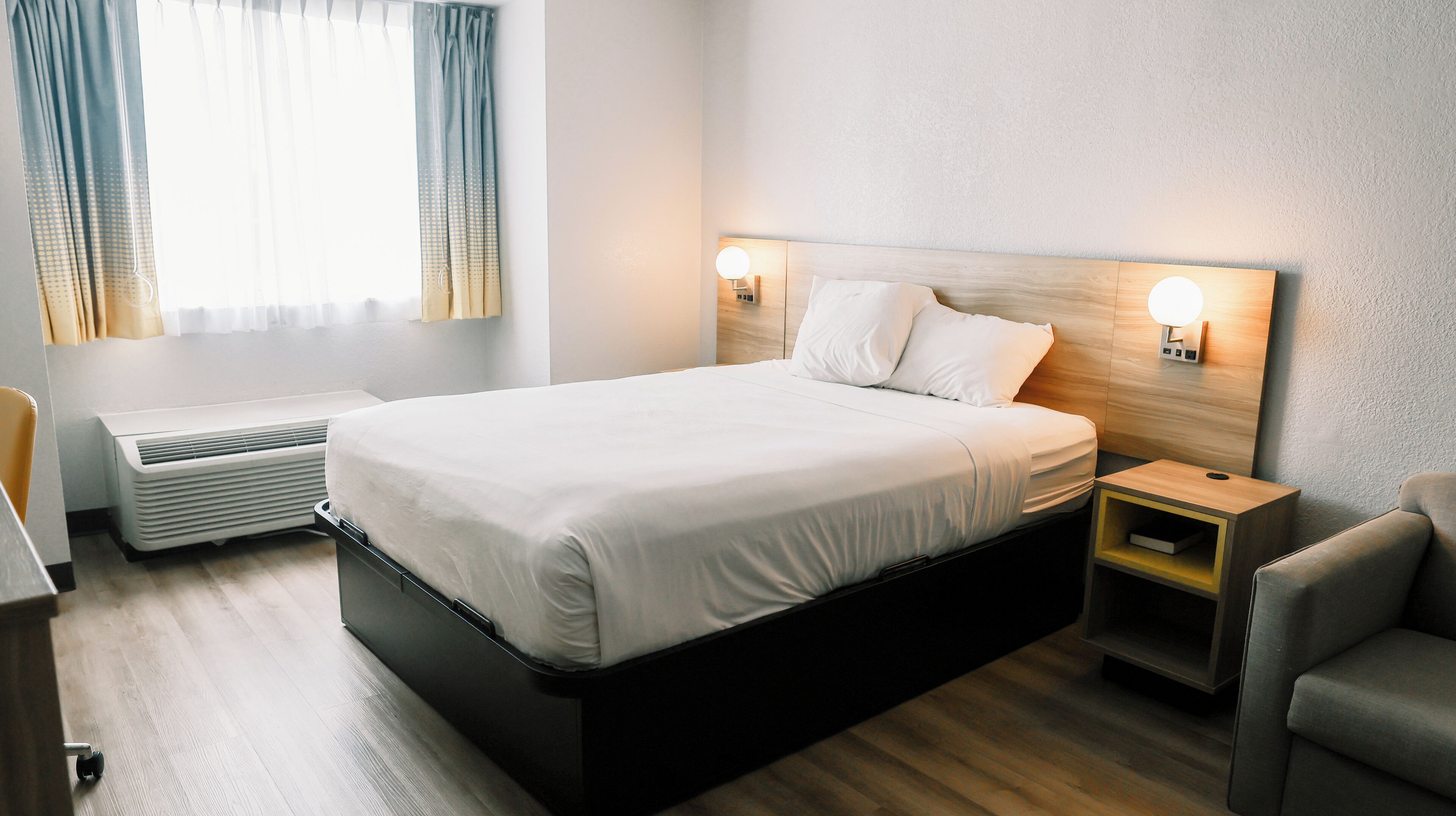 A modern hotel room with a large bed, bedside tables with lamps, a heater, and a view of the outdoors.