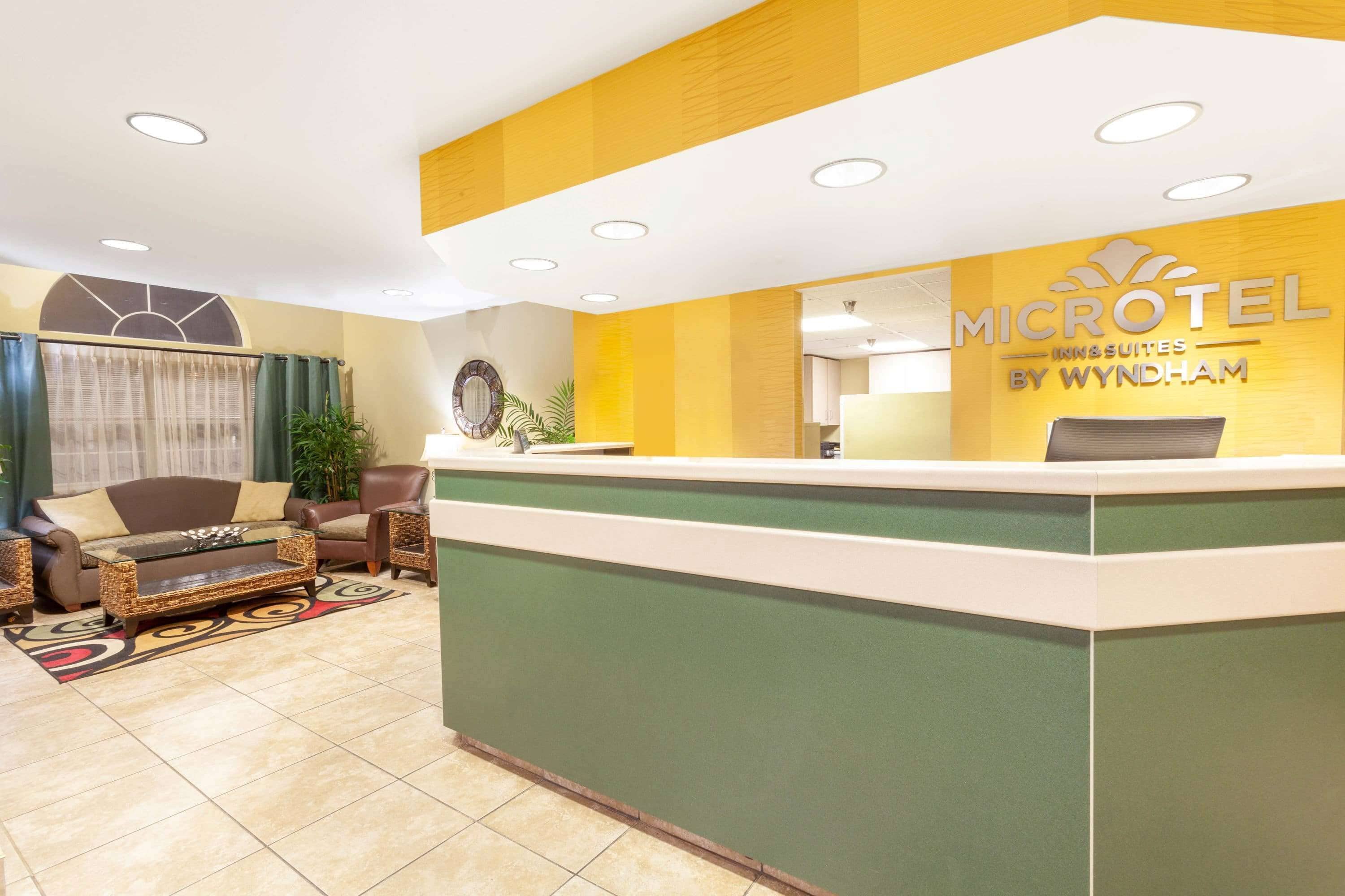 A reception area with a green reception desk, a brown sofa, and a patterned rug.