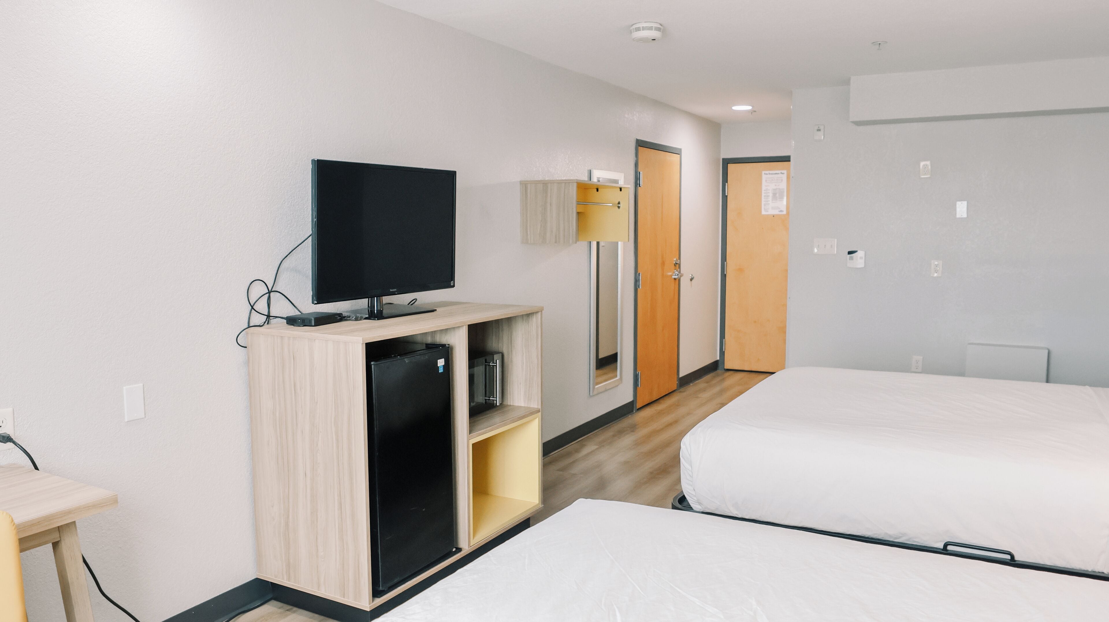 A hotel room with two beds, a TV, a small desk, and a wardrobe.