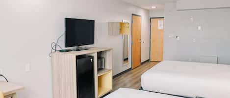 A hotel room with two beds, a TV, a small desk, and a wardrobe.