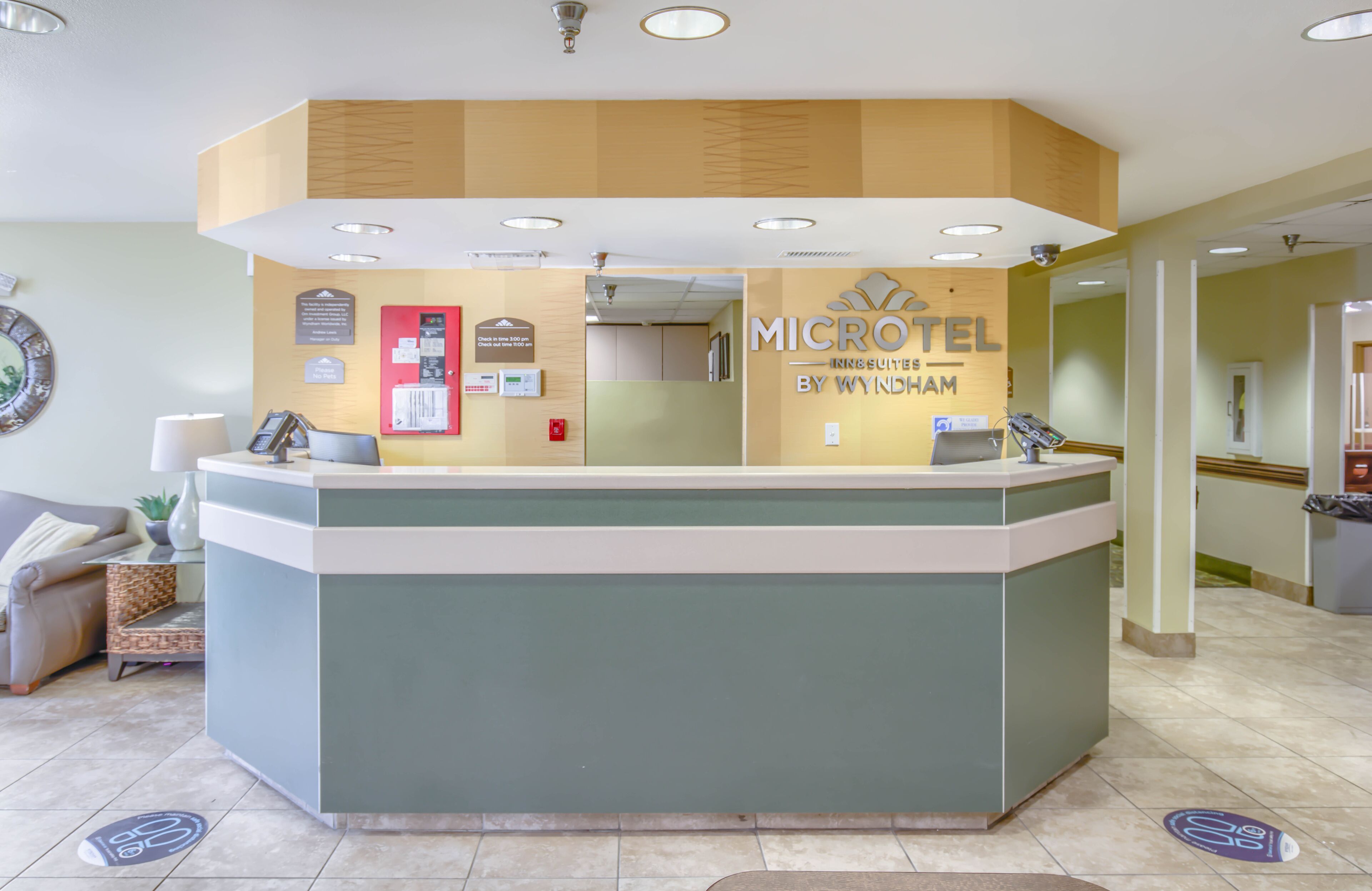 Una recepción con un letrero que dice "MICROHOTEL BY WYNDHAM" y un mostrador con una computadora y un teléfono.