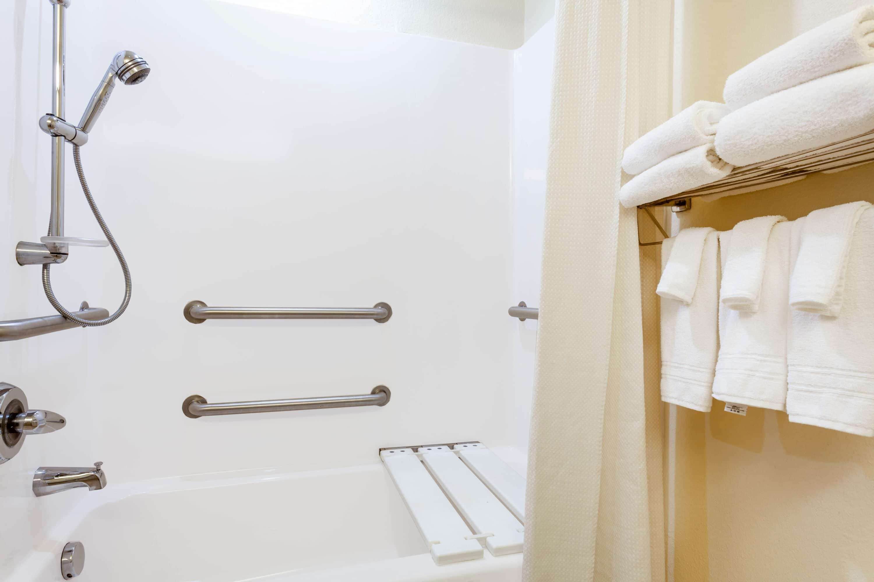 Ein Badezimmer mit einer Badewanne, Haltegriffen und einem Handtuchhalter.