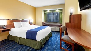 A hotel room with a bed, a desk, a chair, a television, and a window with curtains. - Microtel Inn & Suites by Wyndham Gulf Shores (Gulf Shores)