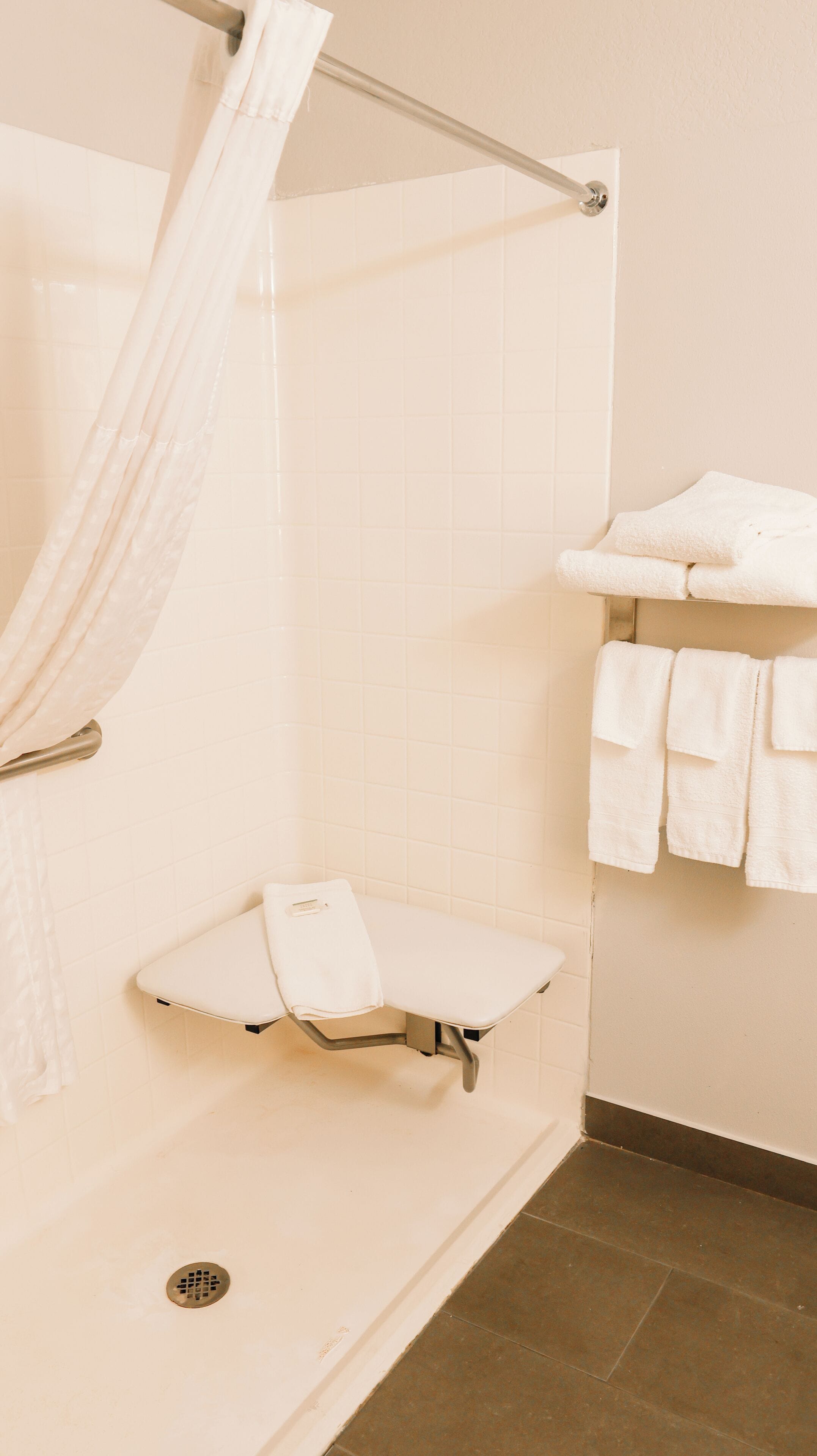 Un baño con ducha, lavamanos y un perchero para toallas.