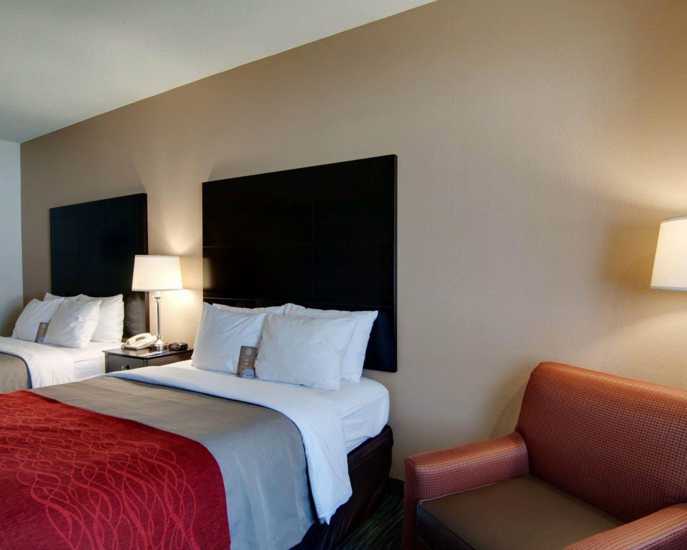 Une chambre d’hôtel avec deux lits, une table de chevet avec une lampe et une chaise.