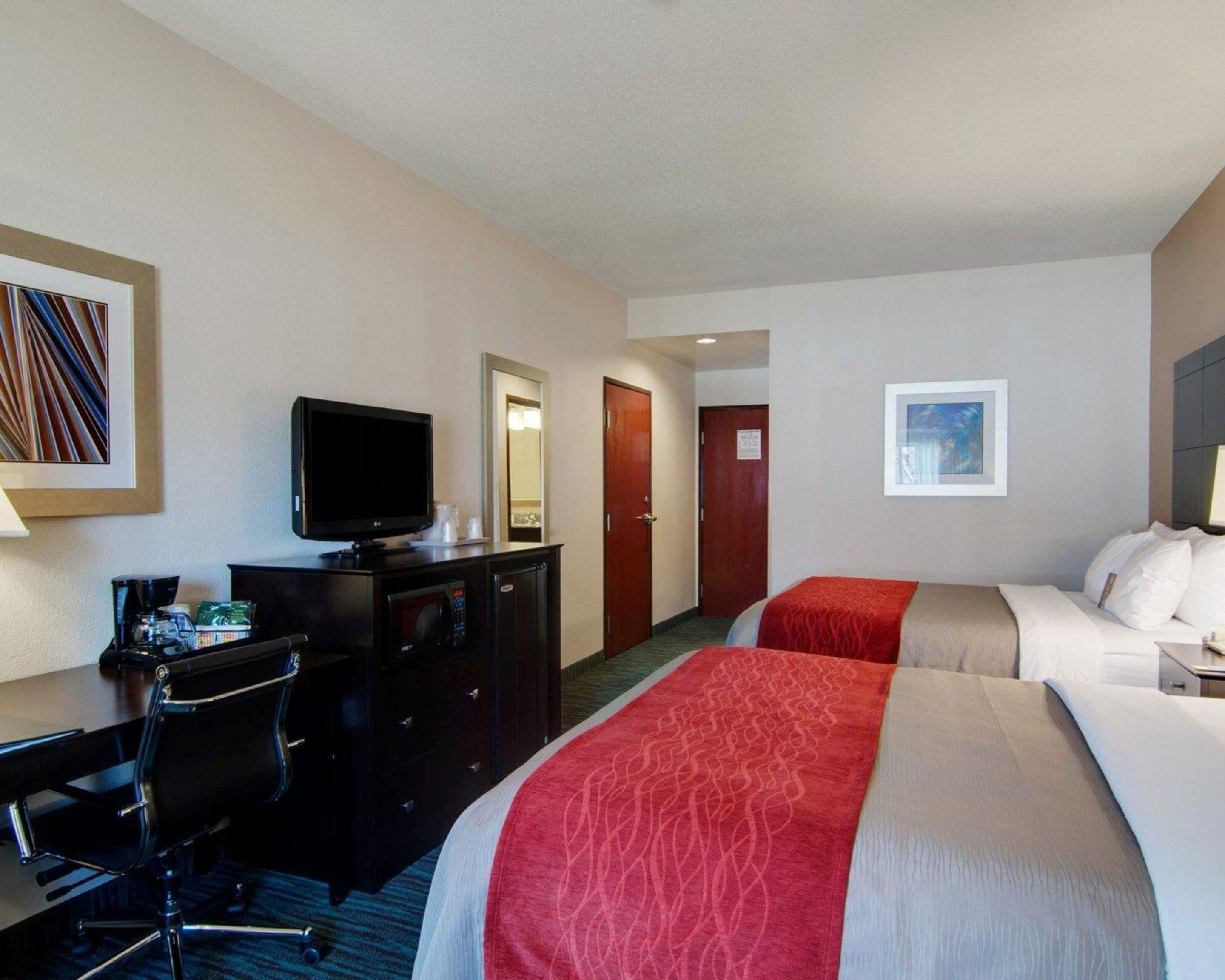 A hotel room with a bed, a desk with a computer, a television, and a mirror.
