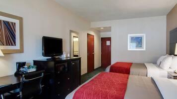 A hotel room with a bed, a desk with a computer, a television, and a mirror.