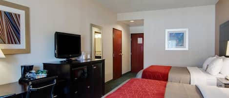 Una habitación de hotel con una cama, un escritorio con una computadora, un televisor y un espejo.