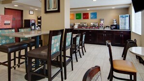 A breakfast area with bar stools, a counter with coffee machines, and a refrigerator.