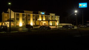 A Comfort Inn hotel at night with illuminated signage, a parking lot with several cars, and a well-lit entrance.