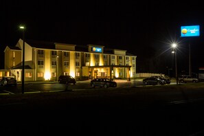 A Comfort Inn hotel at night with illuminated signage, a parking lot with several cars, and a well-lit entrance.