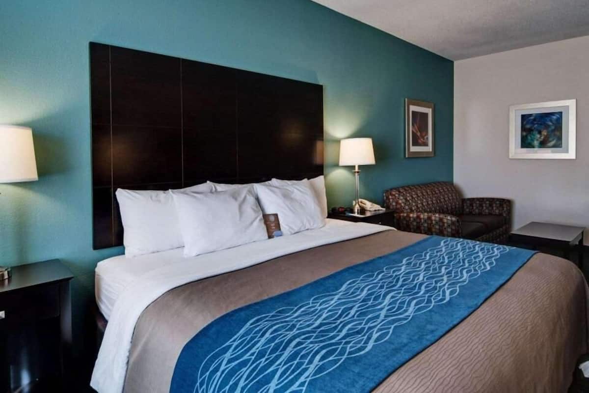 A hotel room with a bed, two bedside tables, a chair, and artwork on the walls.