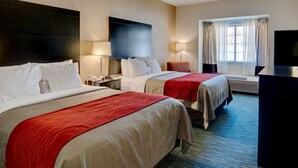 A hotel room with two beds, a flat-screen TV, a desk, and a window with curtains.