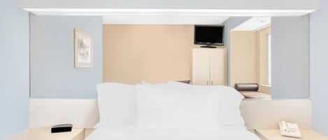 Quarto de hotel moderno com cama, mesas de cabeceira, televisão e telefone.