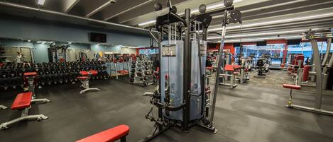 A gym with various exercise equipment, benches, and weight racks.