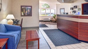 A hotel lobby with a reception desk, a blue sofa, a wooden table, and a framed picture on the wall.