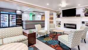 Un vestíbulo de hotel con asientos, televisión, chimenea y zona de refrescos.