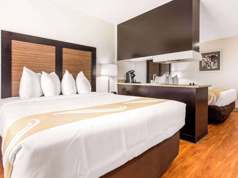 Une chambre d’hôtel avec un grand lit, un petit bureau, un miroir et une machine à café.
